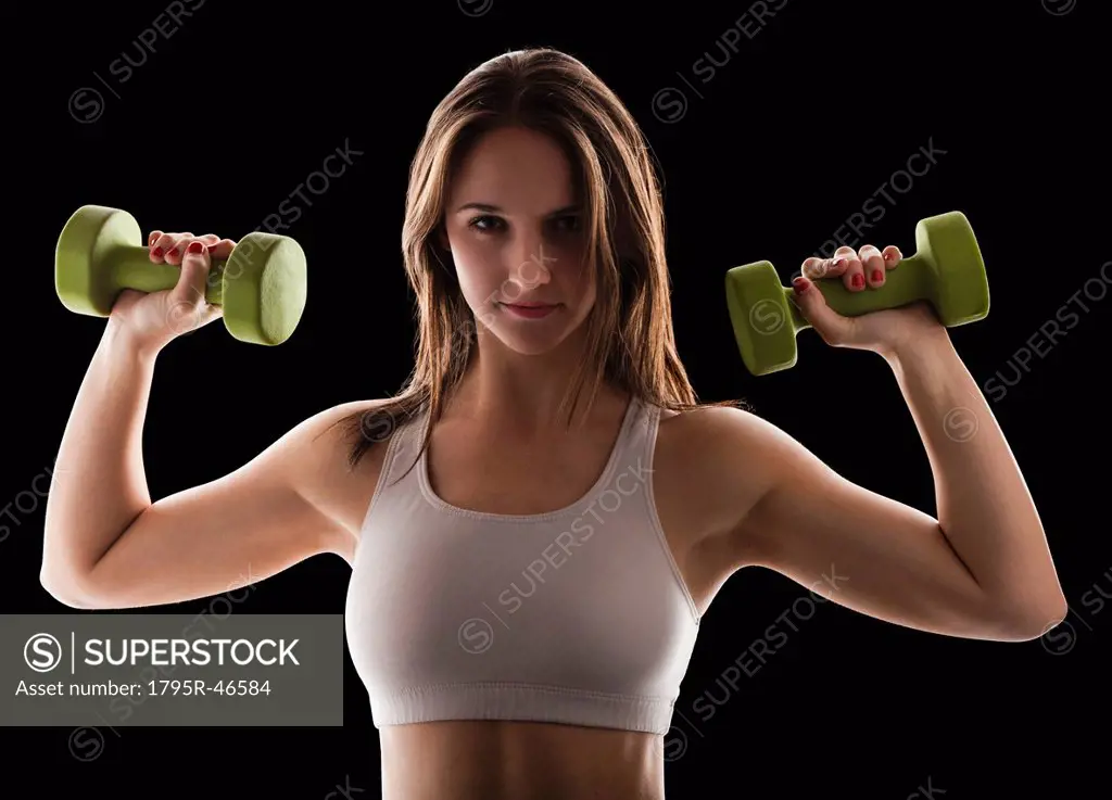 Studio portrait of young woman using hand weights