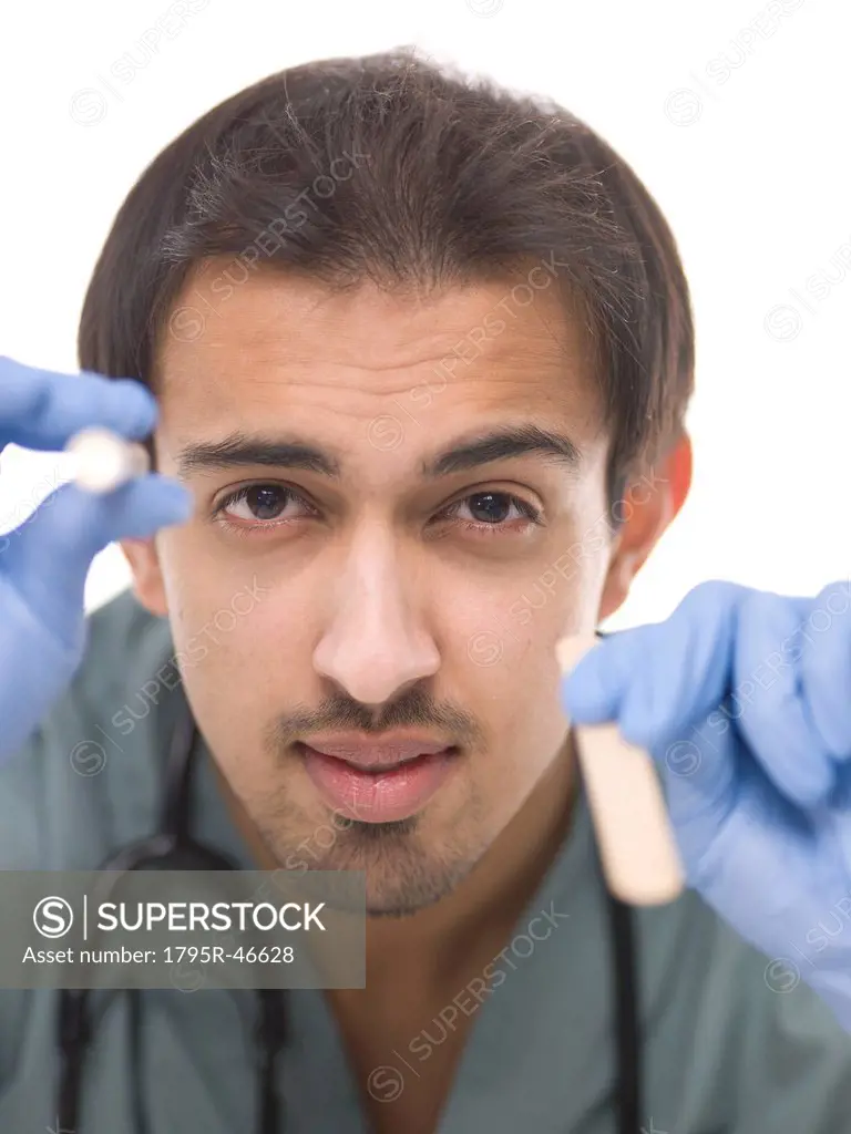 Young surgeon holding small torch in one hand and wooden stick in another