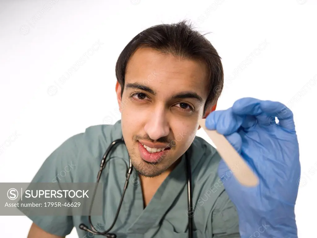Young surgeon holding wooden stick for examining patients throat