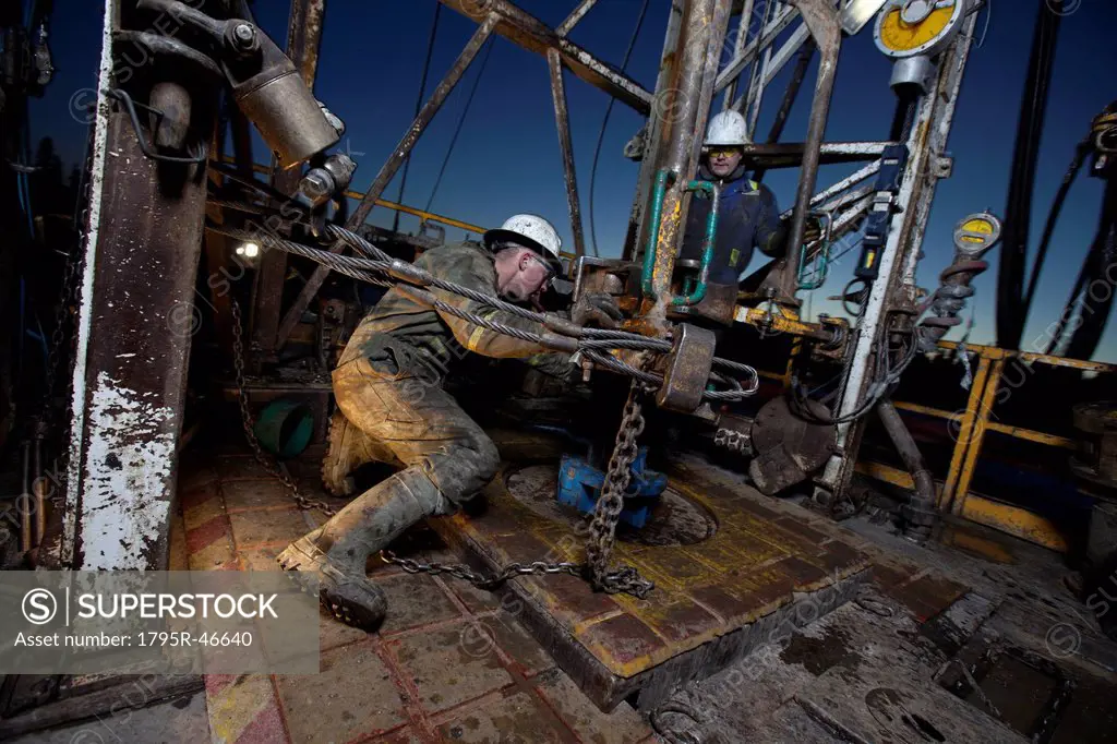 Canada, Alberta, Oil workers using oil drill