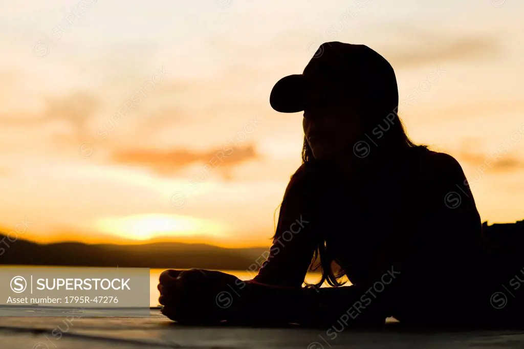 USA, California, Silhouette of young woman relaxing on beach at sunset