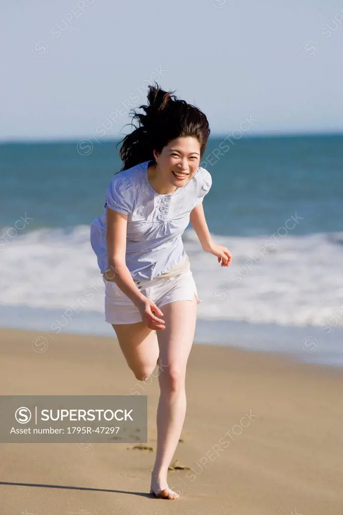 USA, California, Point Reyes, Young woman running on beach