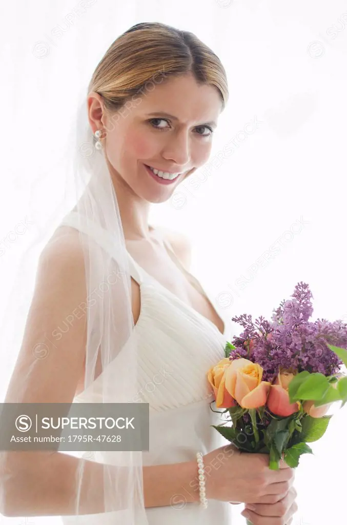 Studio portrait of bride holding floral bouquet