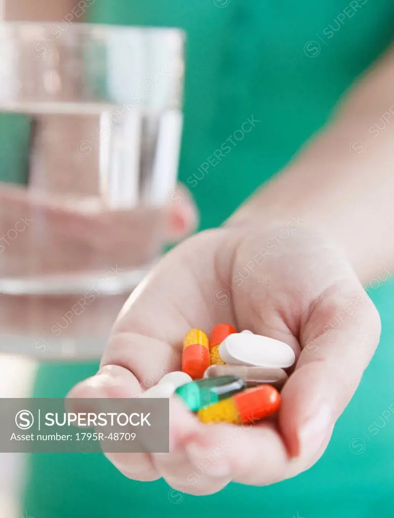 Close up of woman´s hands holding pile of medicines