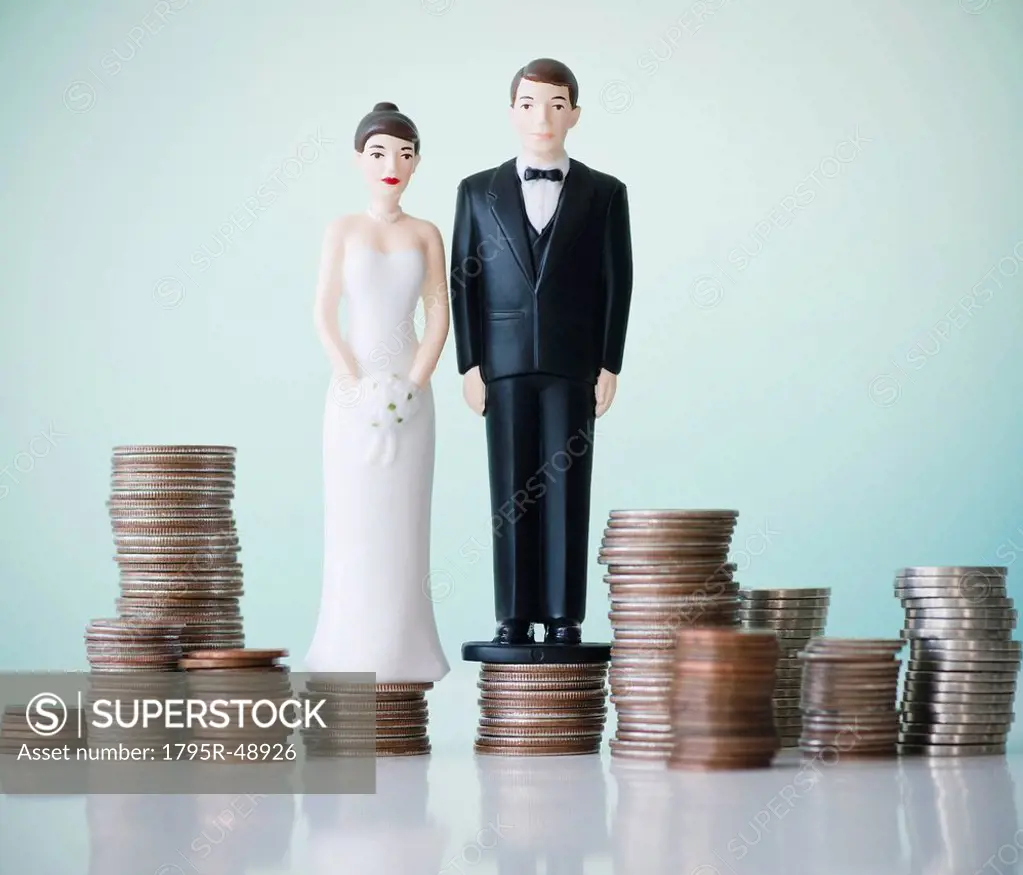 Close up of wedding cake figurines on stacks of coins