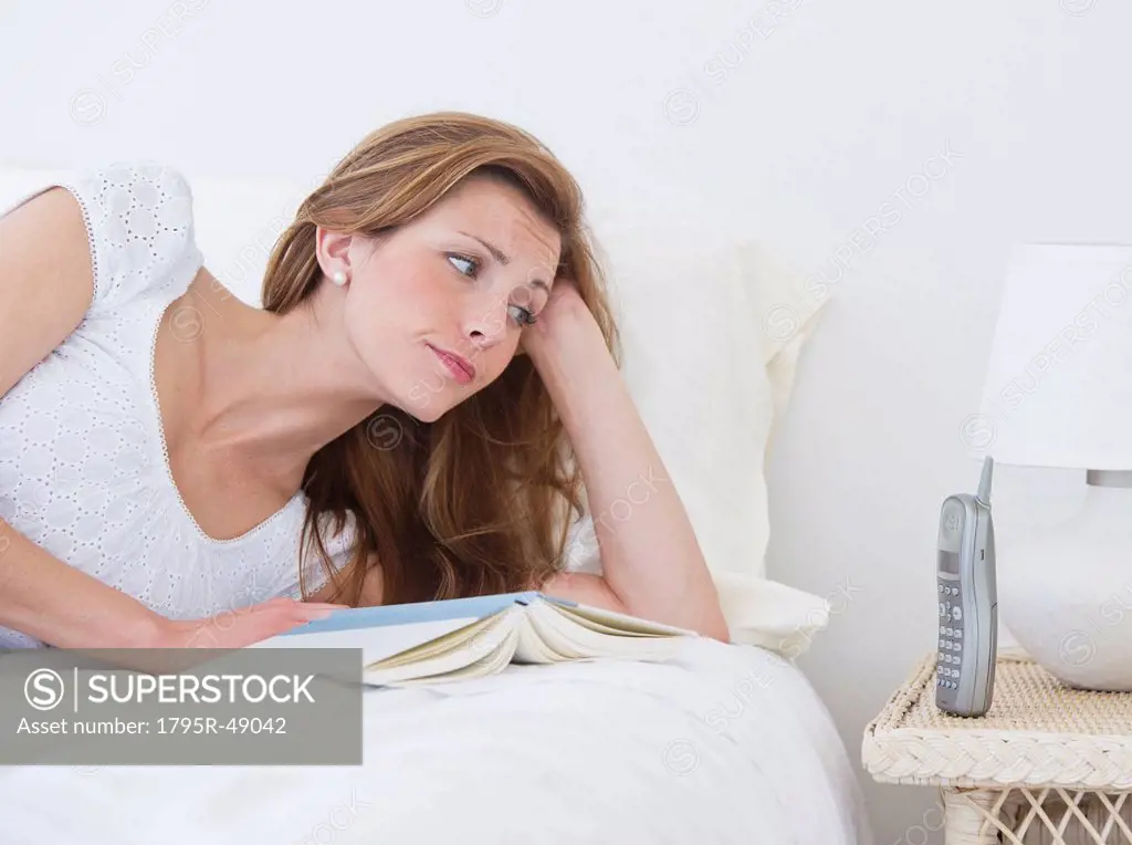 Portrait of young lying on bed and looking at phone