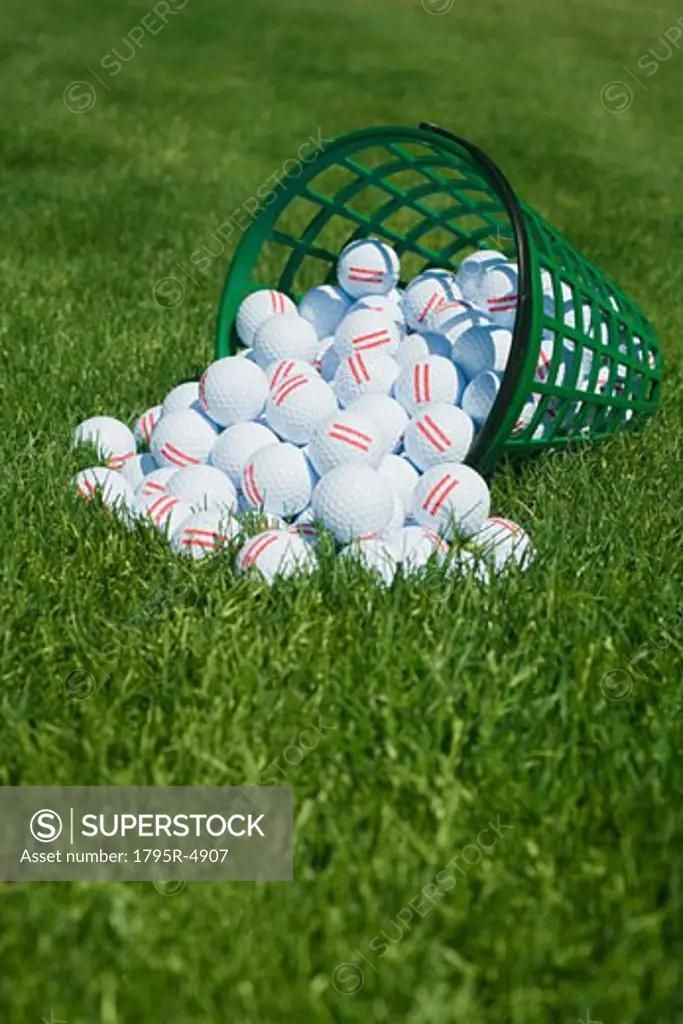 Basket of golf balls spilling onto grass