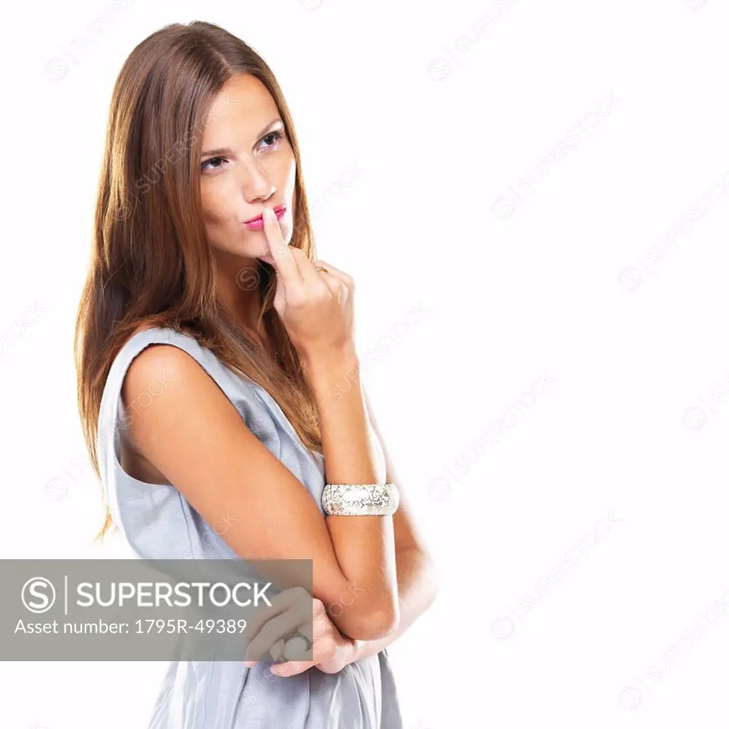Studio shot of young woman on white background with finger on lips