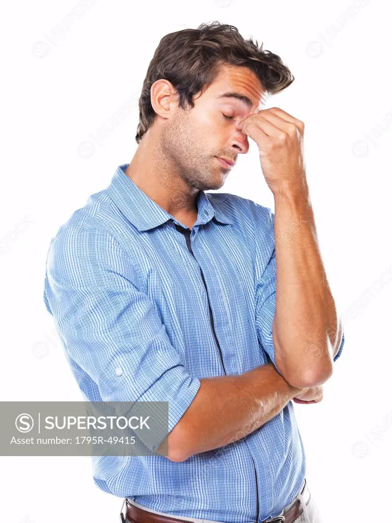 Studio shot of young business man with eyes closed rubbing nose