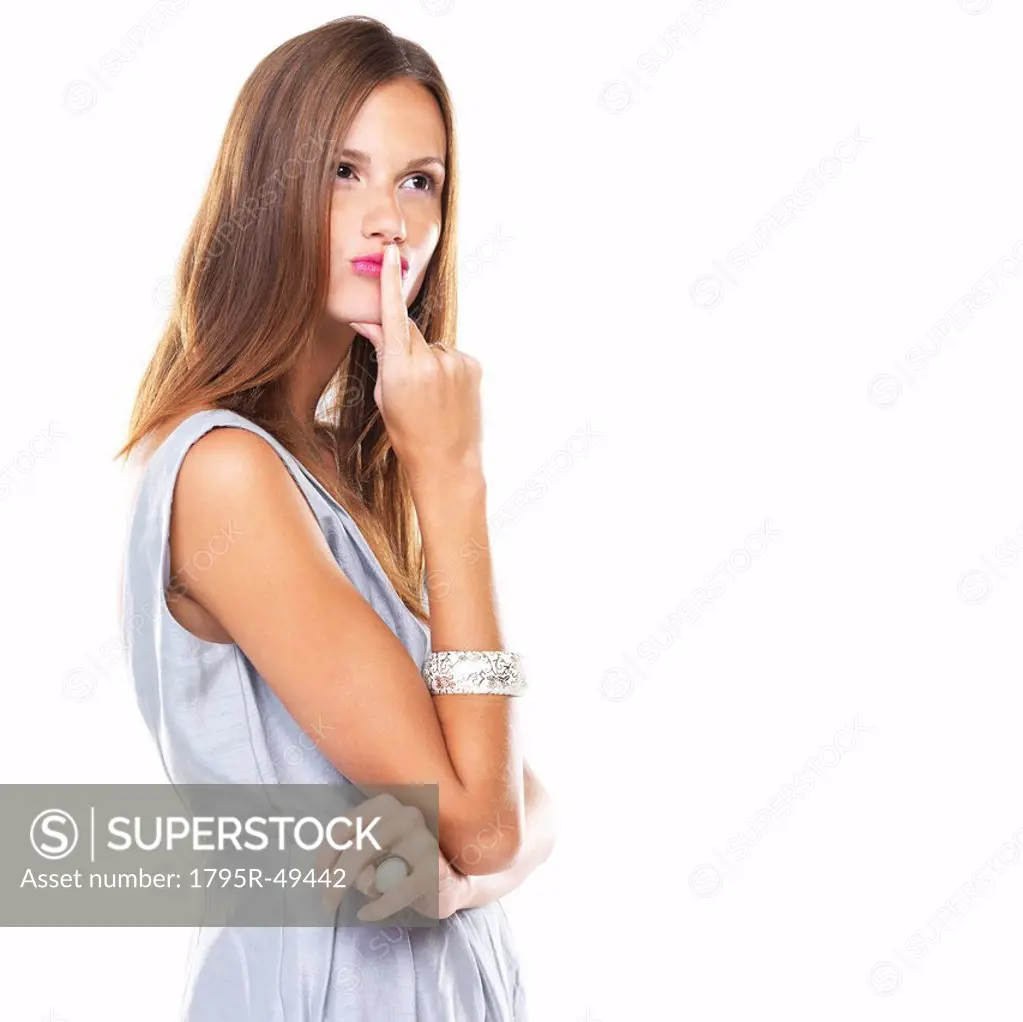 Studio shot of young woman with finger on lips
