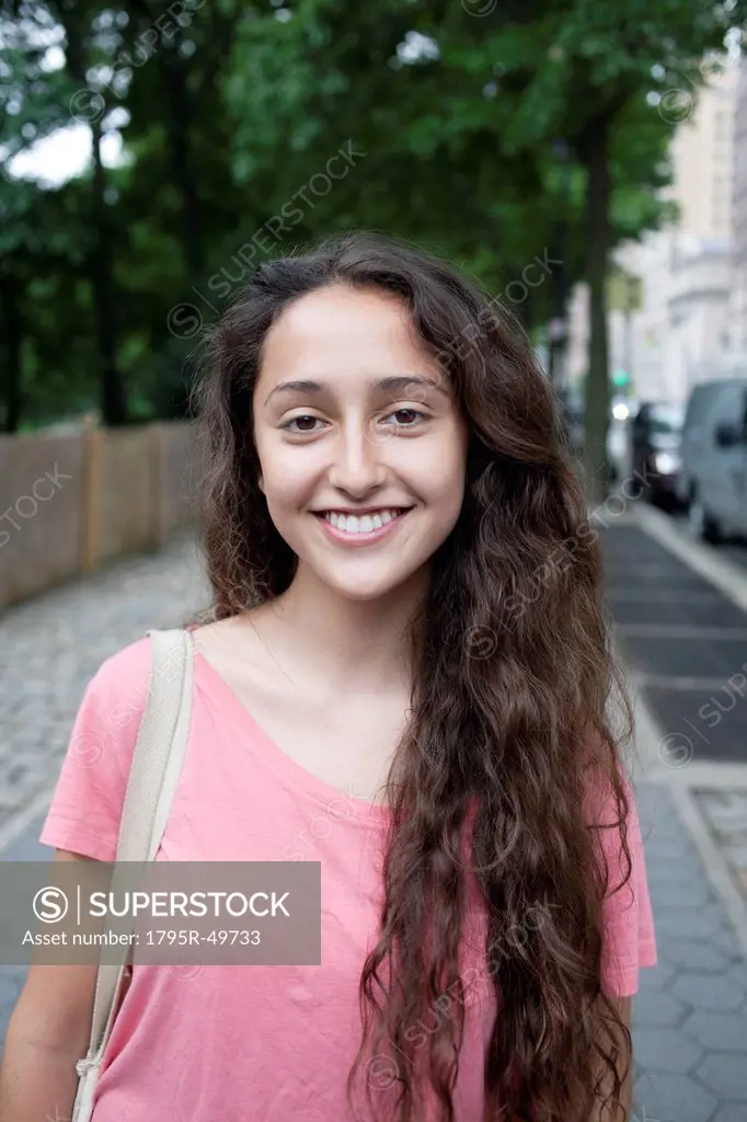 USA, New York, New York City, Portrait of smiling young woman standing on street