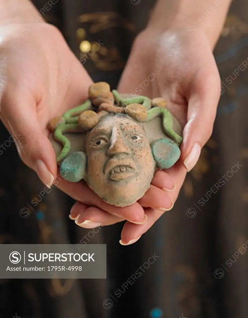 Close-up of woman's hands holding clay face