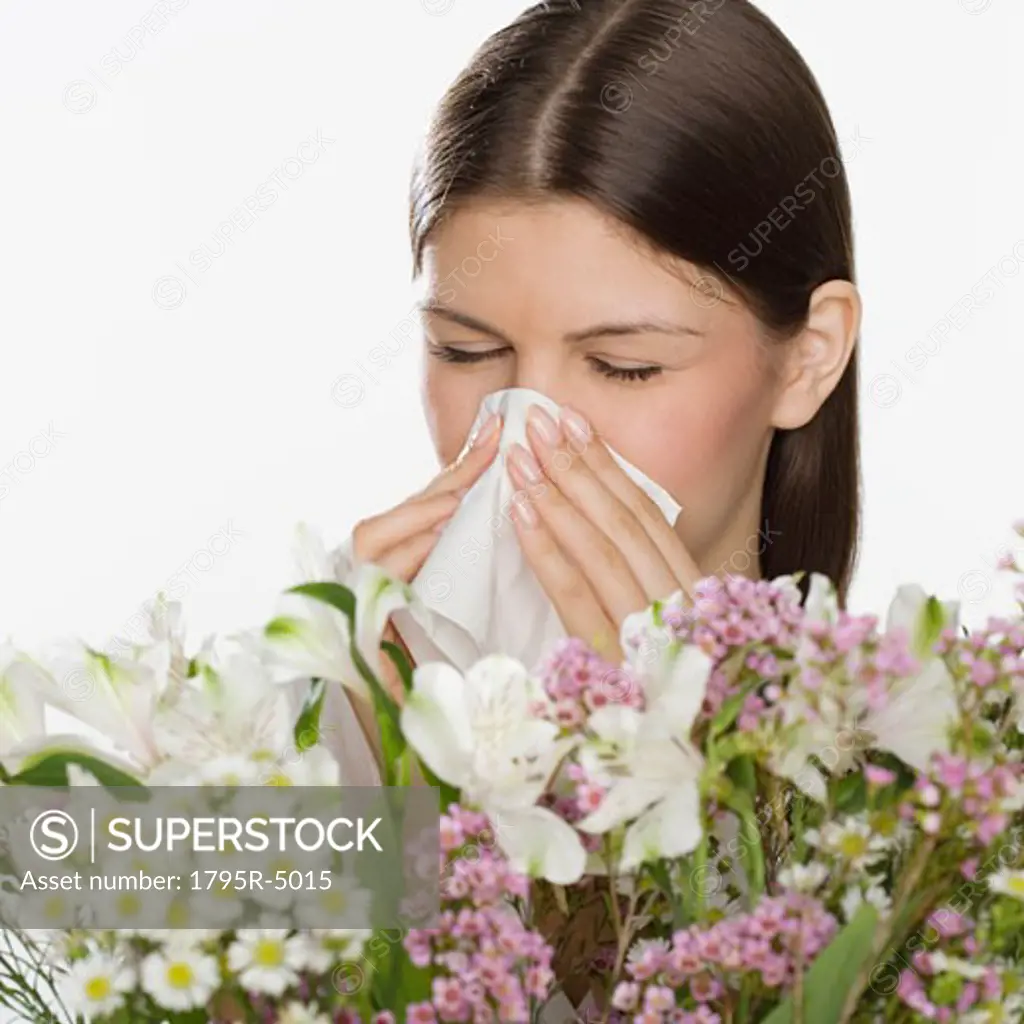 Woman blowing nose next to flowers