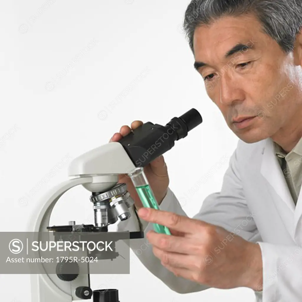 Man with vial of fluid and microscope