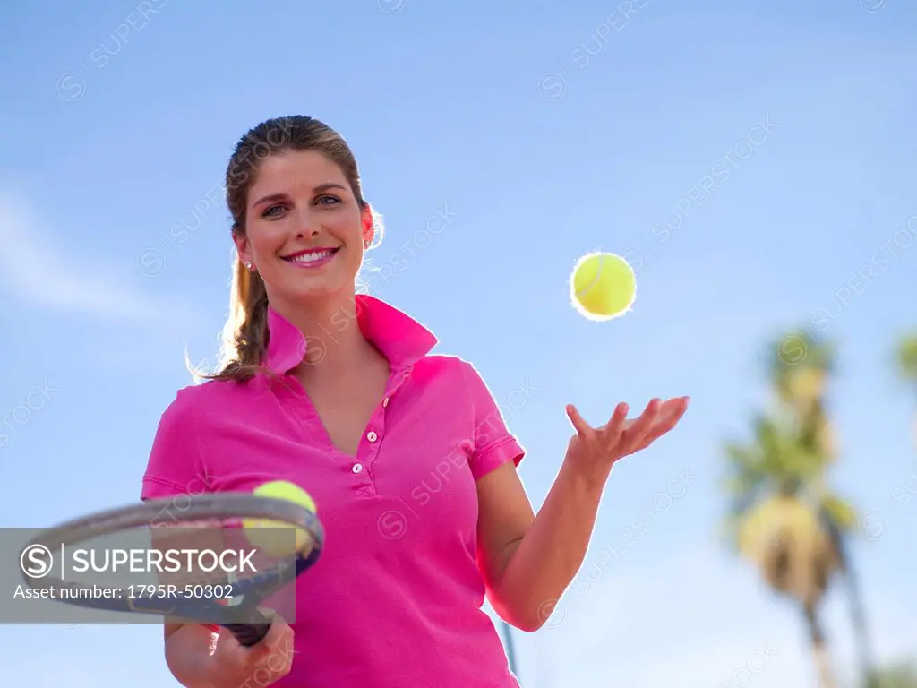 Young woman with tennis balls and racket