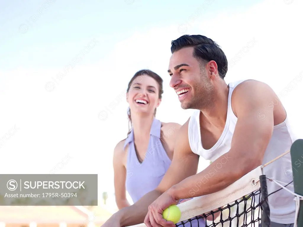 Smiling couple standing near tennis net