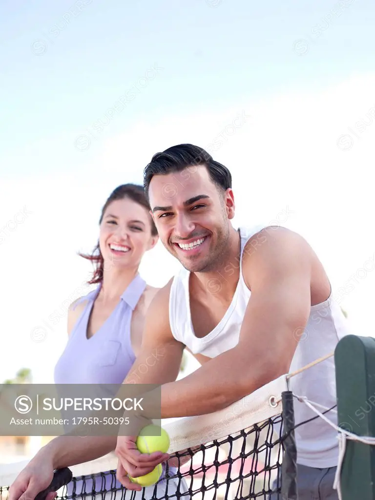Smiling couple standing near tennis net