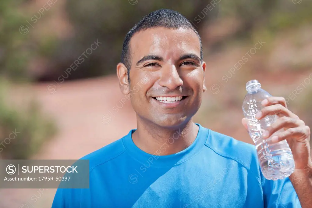Smiling man drinking water after jogging