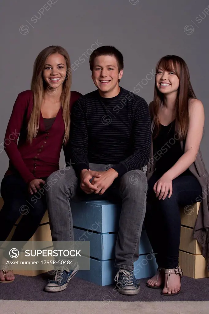 Portrait of teenage boy 16_17 and girl 16_17 with young friend, studio shot