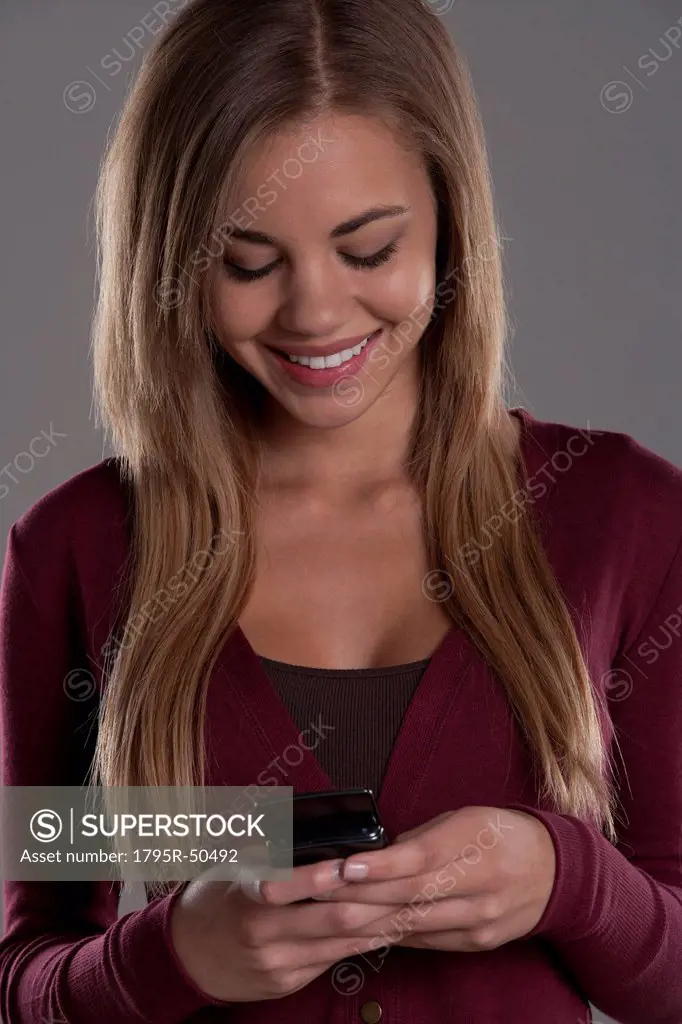 Portrait of teenage girl 16_17 with mobile phone, studio shot