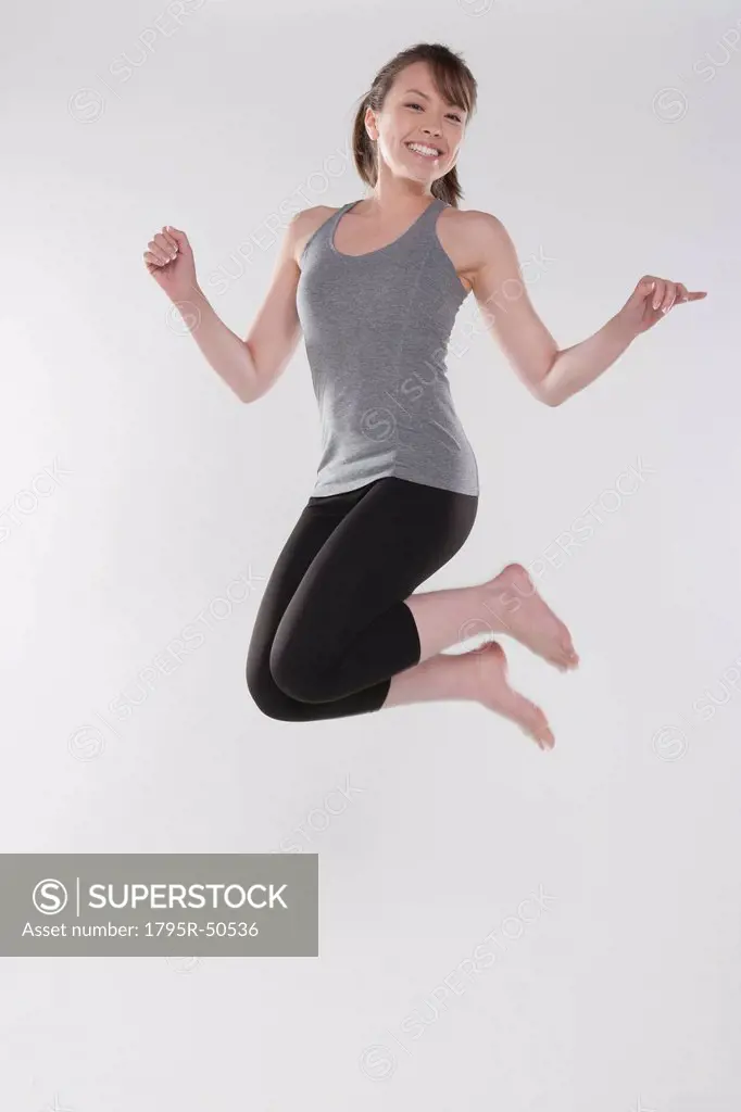 Portrait of young woman jumping, studio shot