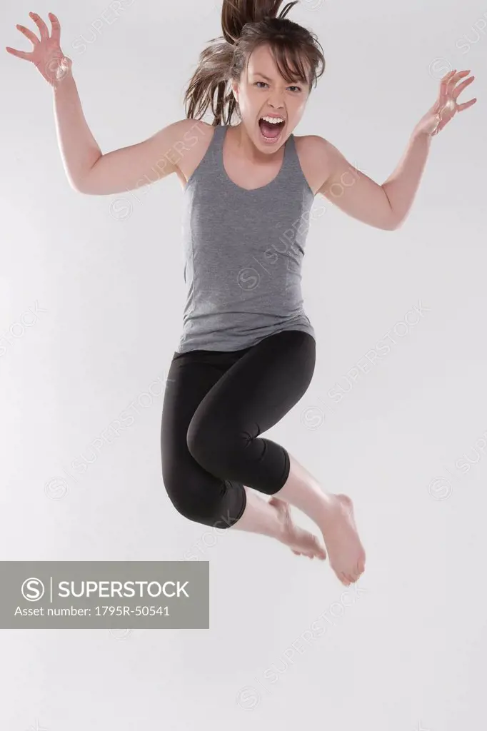 Portrait of young woman jumping, studio shot