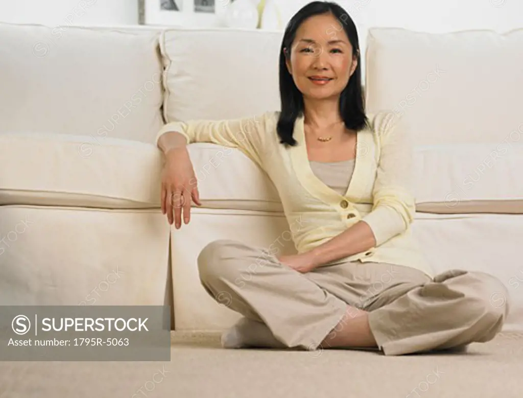 Middle-aged Asian woman leaning on sofa smiling