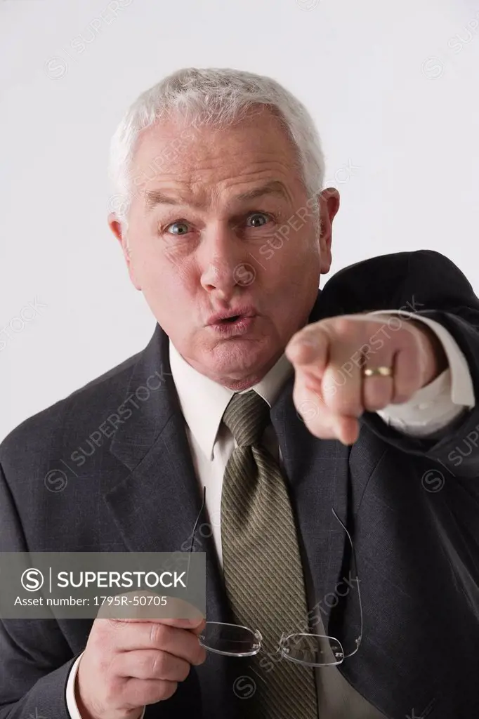 Portrait of senior businessman pointing, studio shot