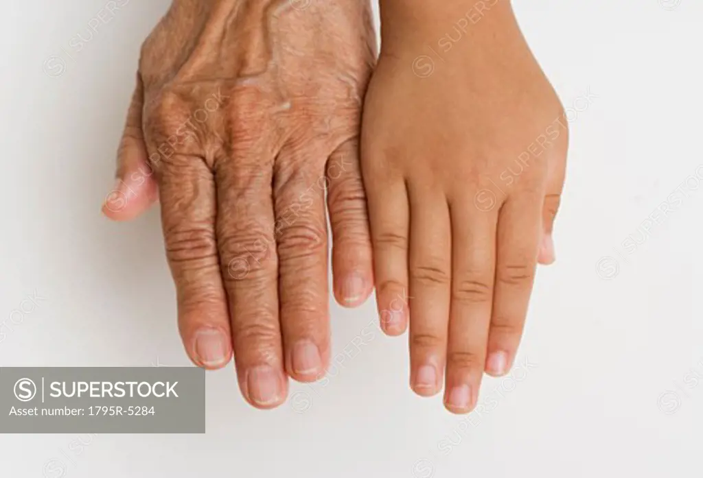 Close-up of child's hand next to senior's hand