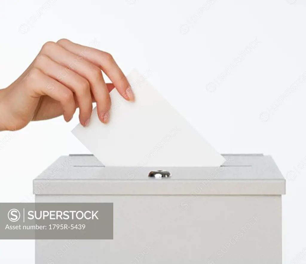 Close-up of woman's hand putting card in box with slot