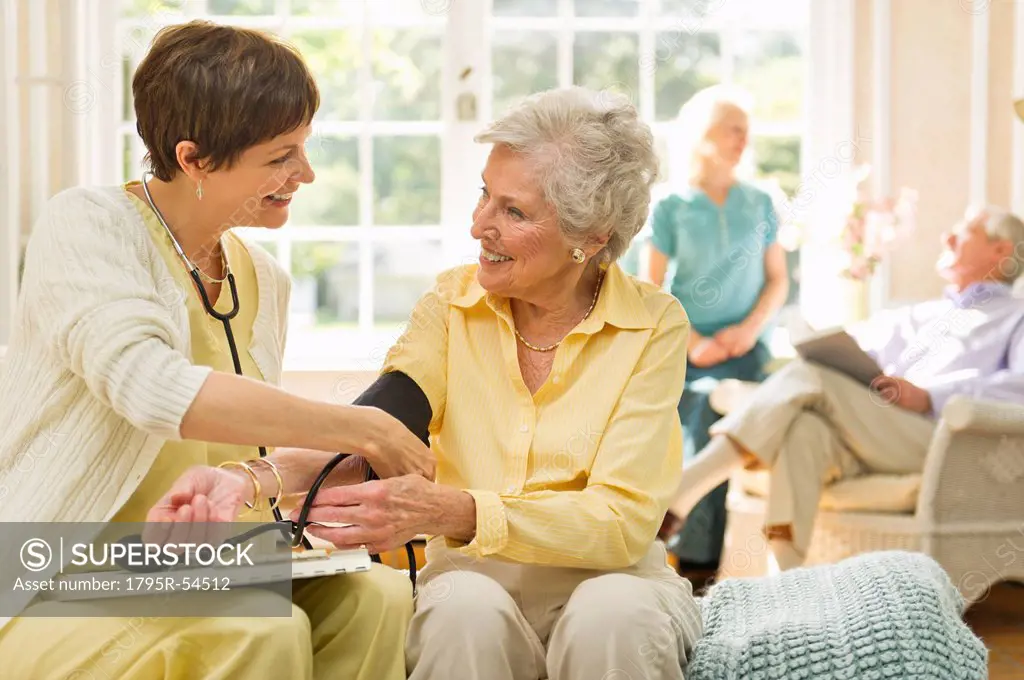 Nurse taking pulse of senior woman in nursing home