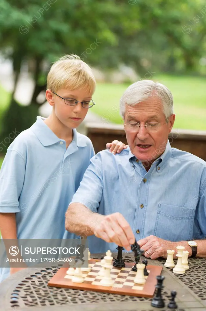 Grandfather teaching grandson 10_11 how to play chess