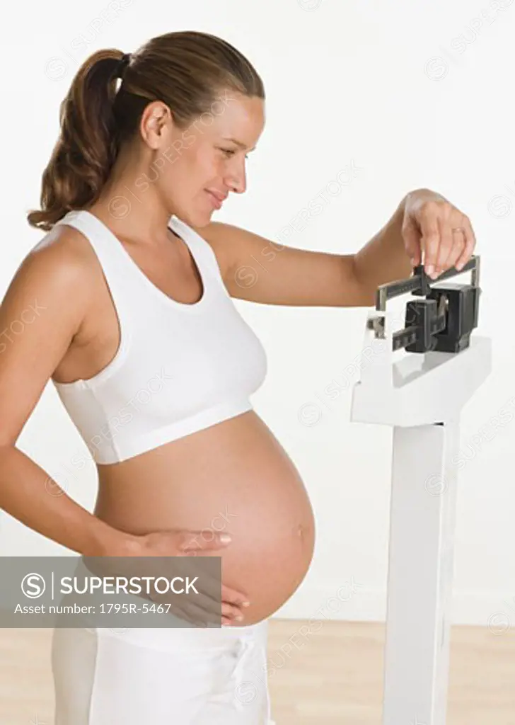 Pregnant woman weighing self on scale