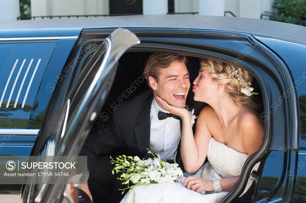 Newly wed couple sitting in limousine