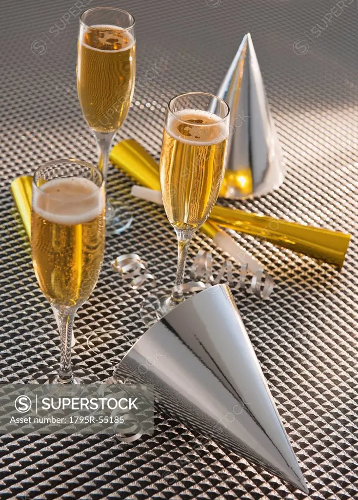 Flutes with champagne, party horn blowers and paper party hats