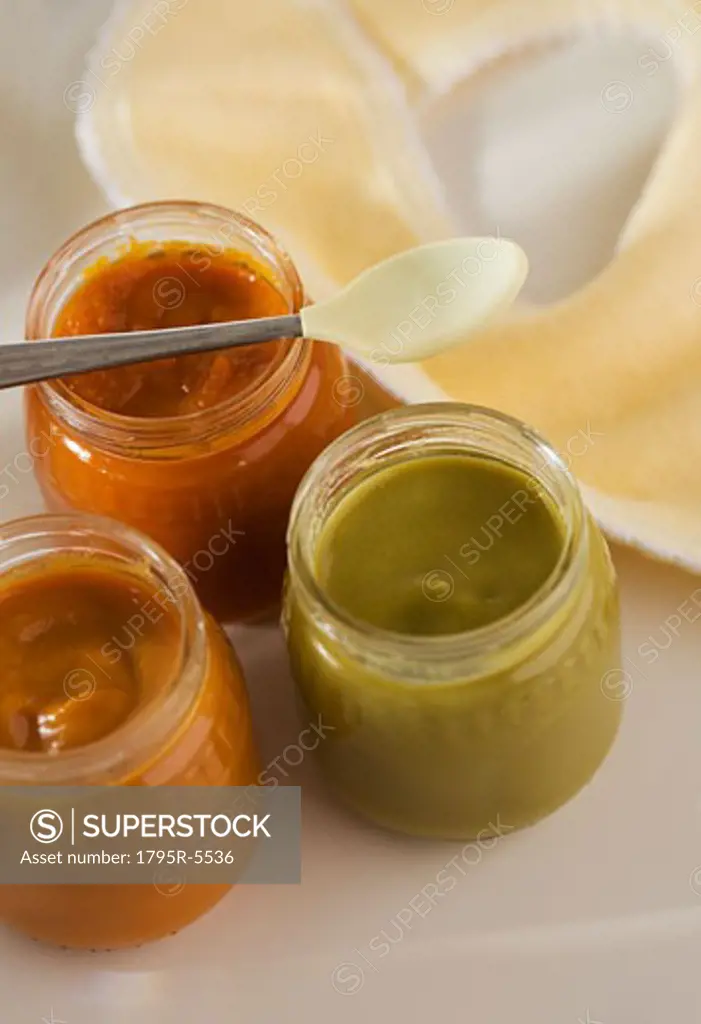 Close-up of baby food in jars with spoon and bib