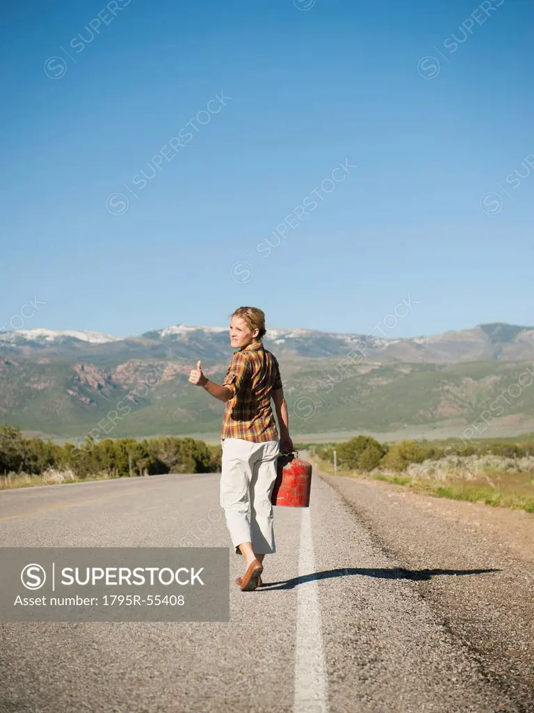Mid adult woman carrying empty canister attempting to stop vehicles for help