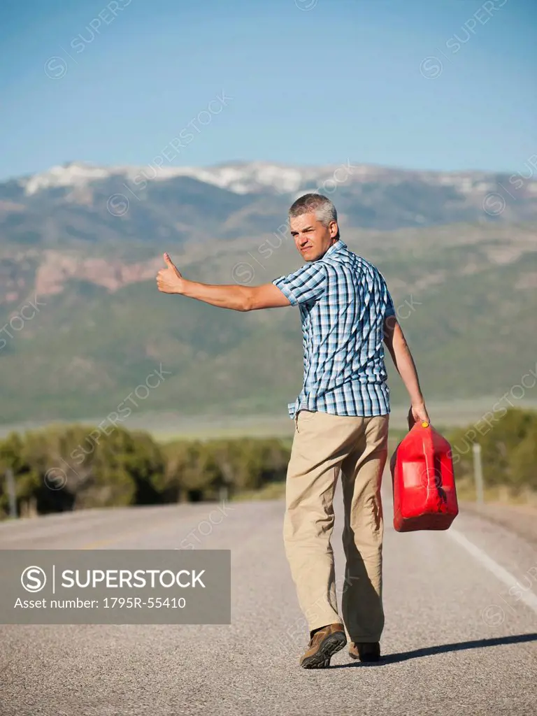 USA, Utah, Kanosh, Mid adult man carrying empty canister attempting to stop vehicles for help