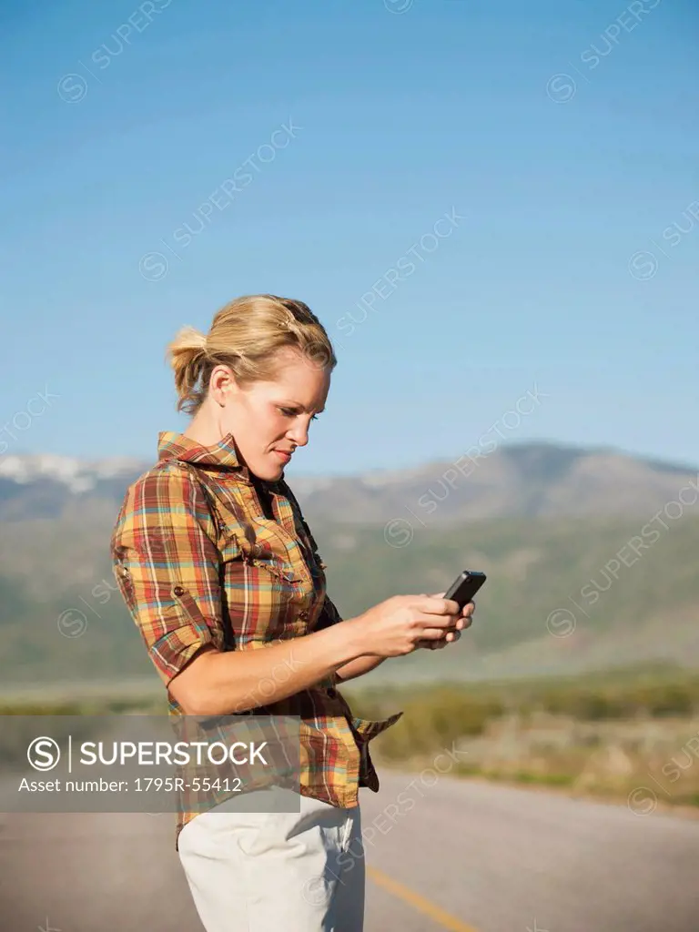 USA, Utah, Kanosh, Mid adult woman calling emergency services on empty desert road