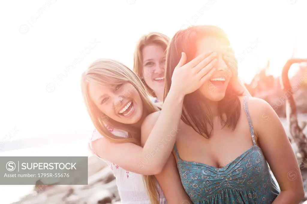 Three young women hanging out, covering eyes and laughing