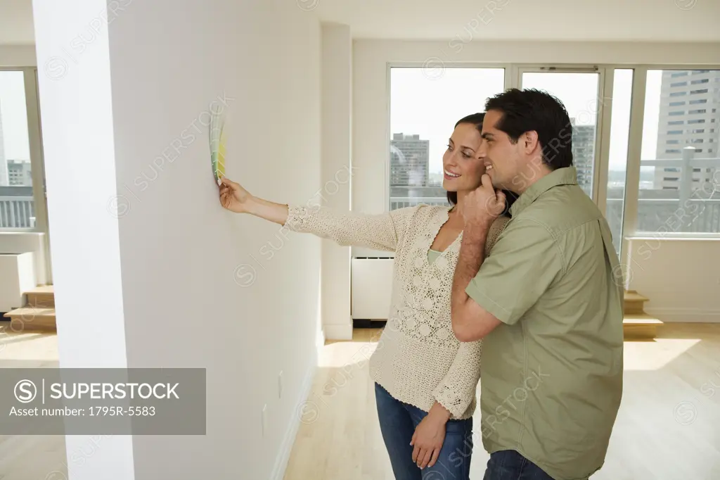 Couple holding paint swatches up to wall