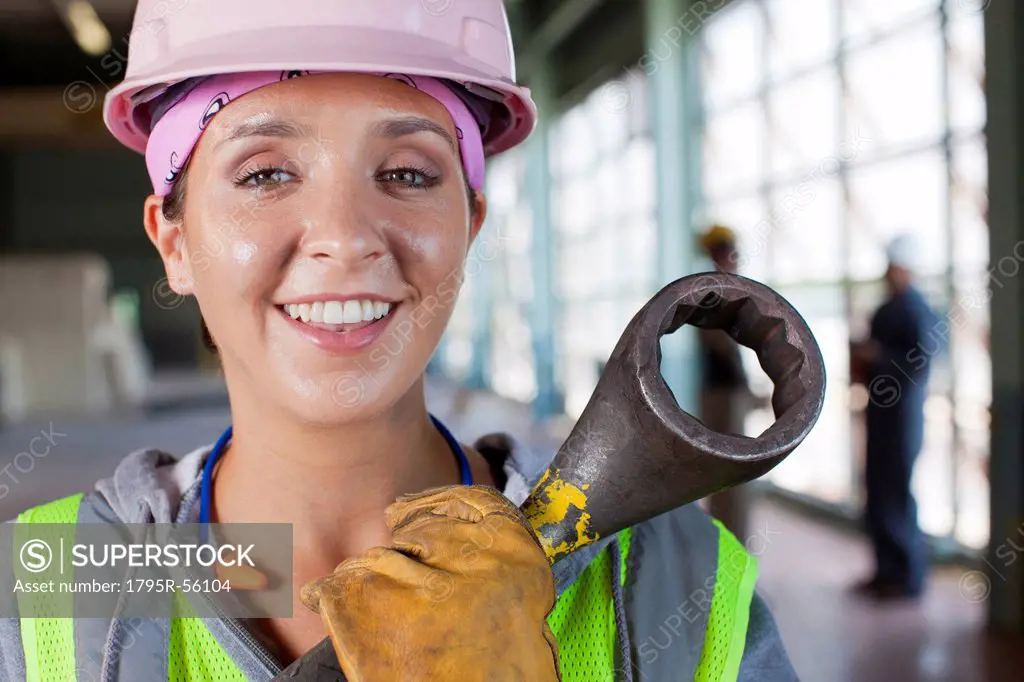 Portrait of female manual worker wearing hardhat holding tool