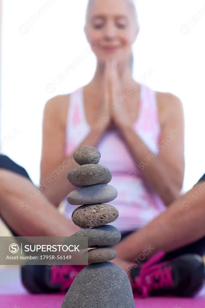 Woman doing yoga behind stack of pebbles