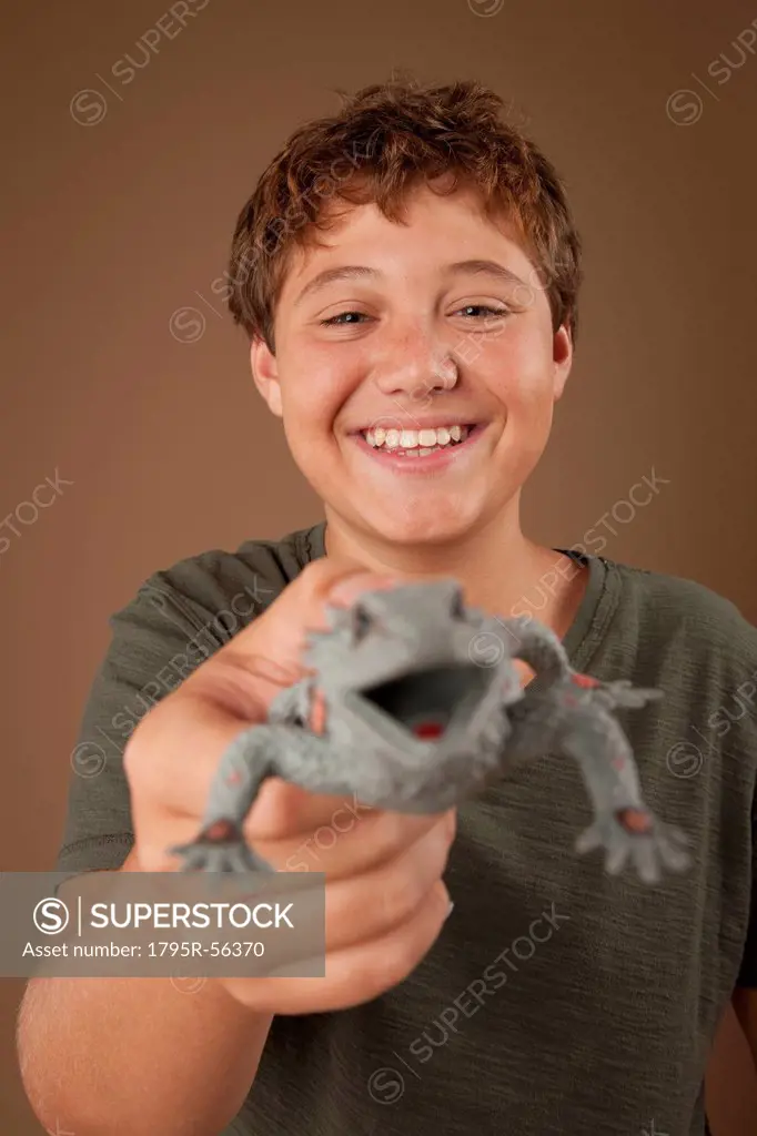 Studio portrait of boy 12_13 holding plastic animal