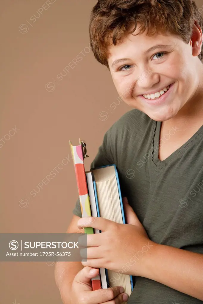 Studio portrait of boy 12_13 holding books