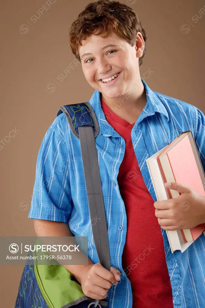 Studio portrait of boy 12_13 with backpack and books