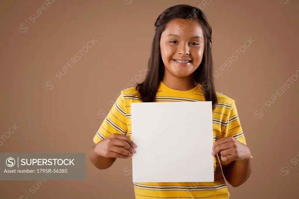 Studio portrait of girl 10_11 holding blank sheet of paper