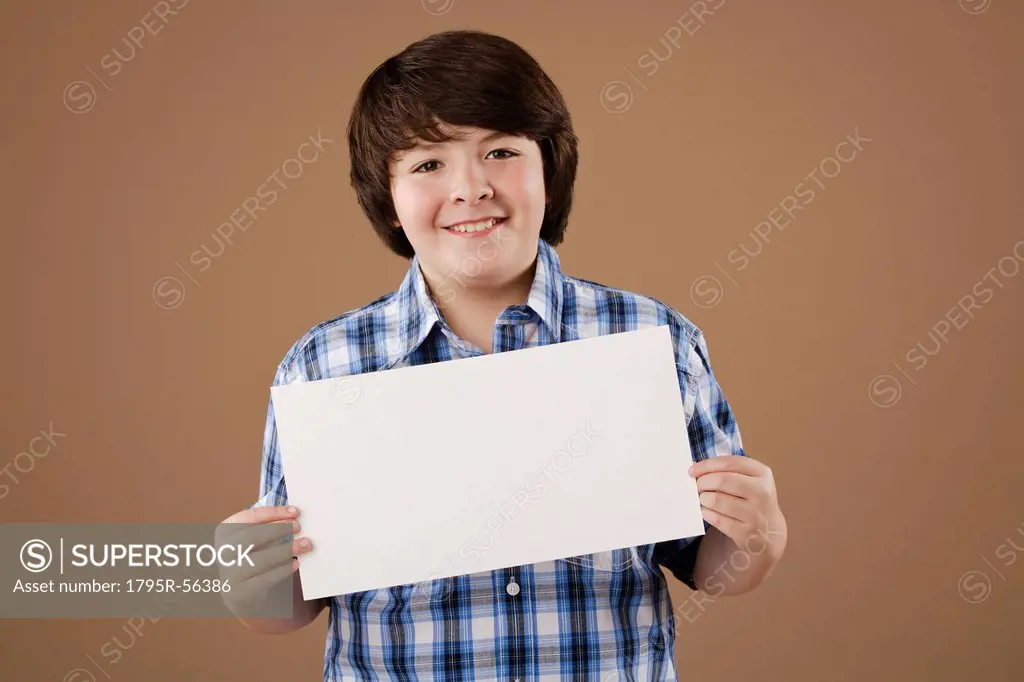 Studio portrait of boy 10_11 holding blank sheet of paper