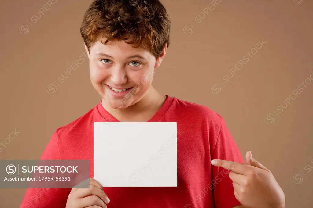 Studio portrait of boy 12_13 holding blank sheet of paper