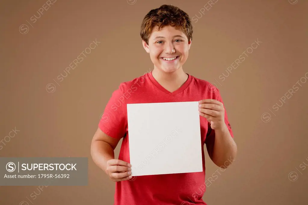 Studio portrait of boy 12_13 holding blank sheet of paper